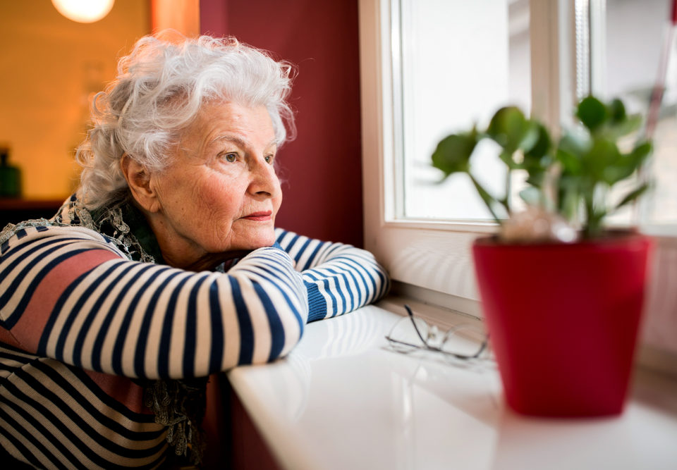 Older Senior Adult looking out the window.