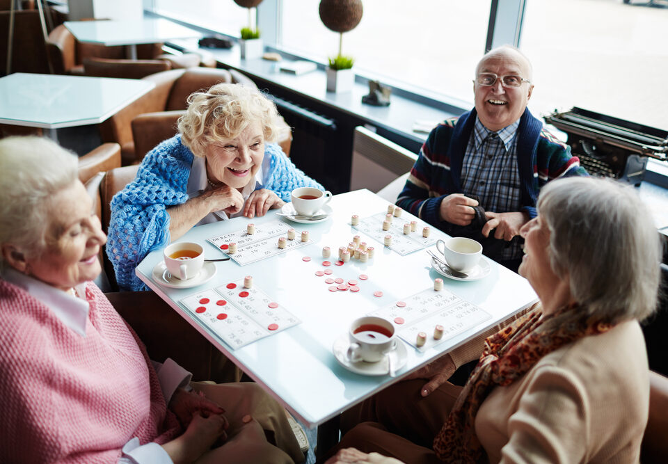 Group,Of,Elderly,People,Sitting,By,Table,,Talking,And,Playing