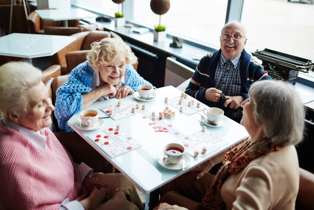 Group,Of,Elderly,People,Sitting,By,Table,,Talking,And,Playing